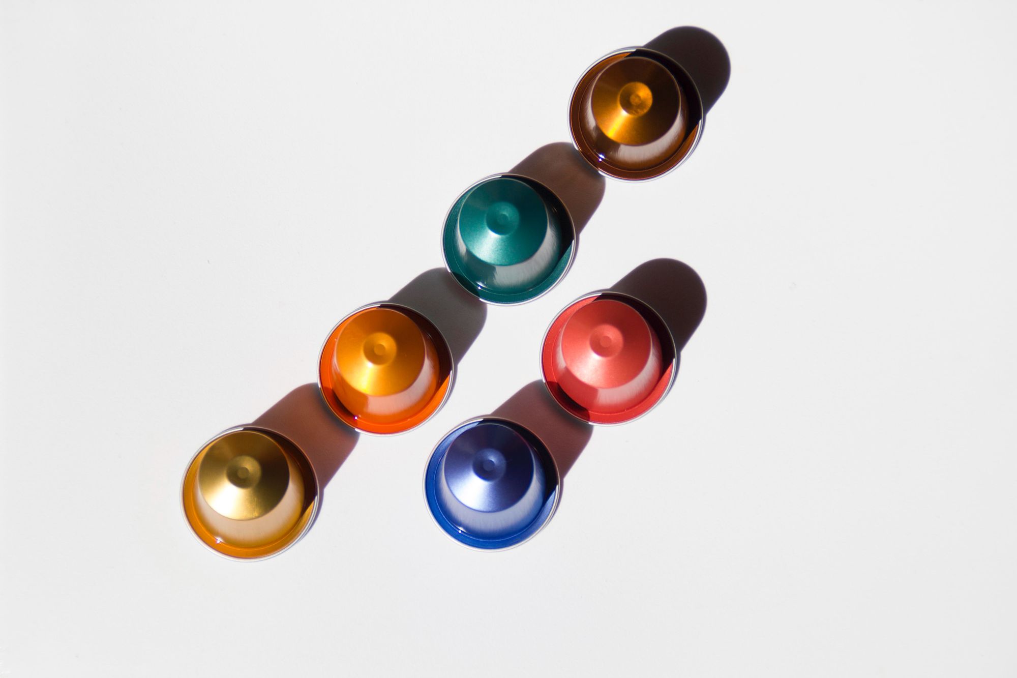 6 nespresso capsules in different colors layng on white table